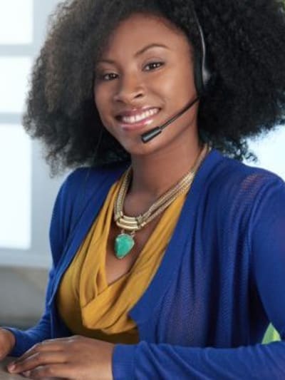 Person wearing headset sits at desktop computer.